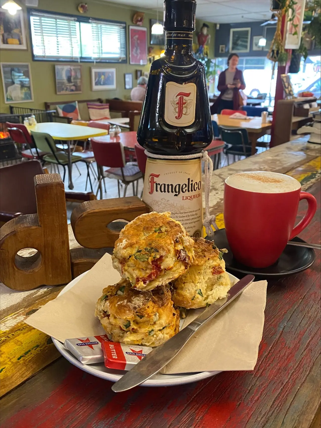 Savoury scones and a red coffee cup on a colourful café table.